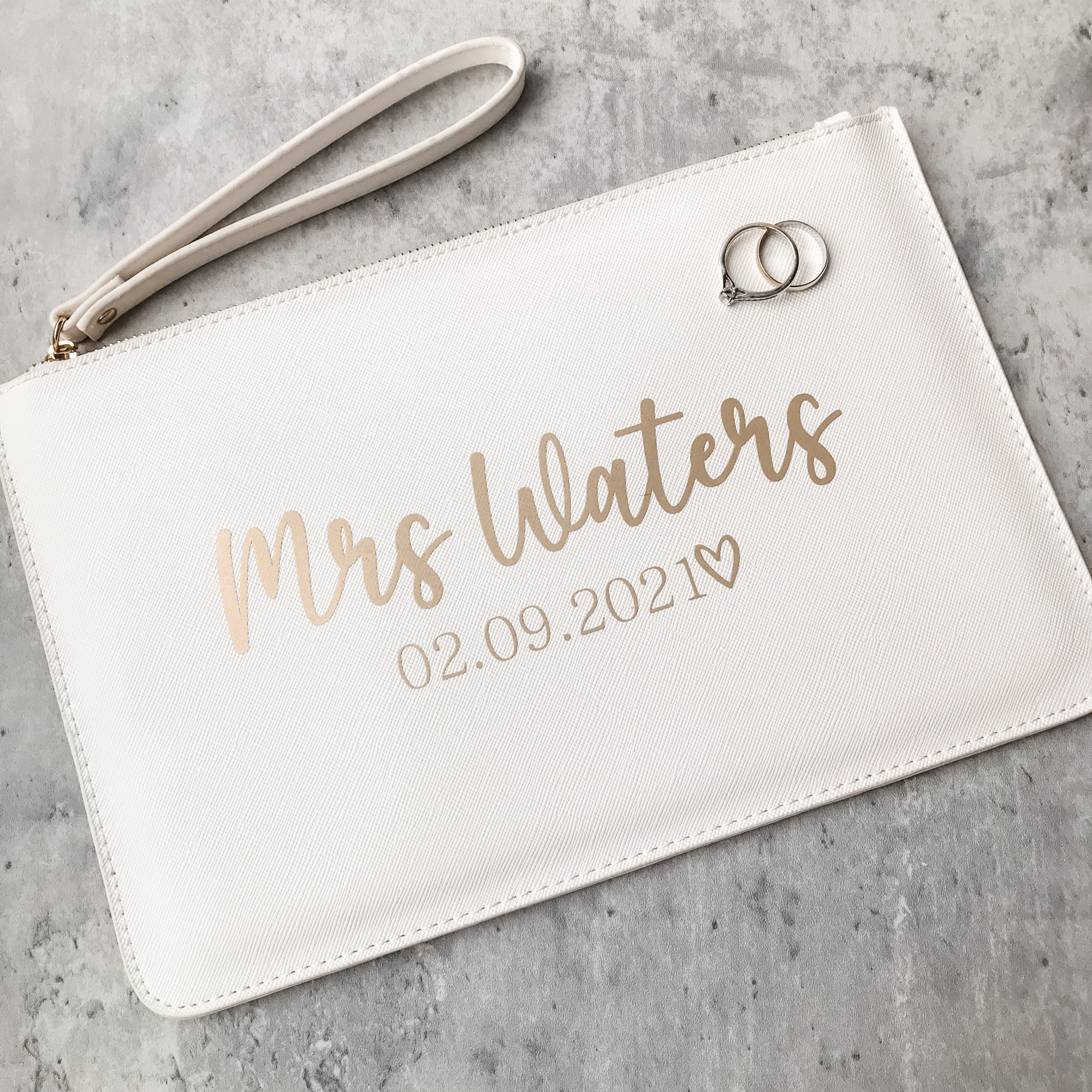 Personalised white bridal clutch bag featuring a custom Mrs surname and wedding date text detail for a bride gift.