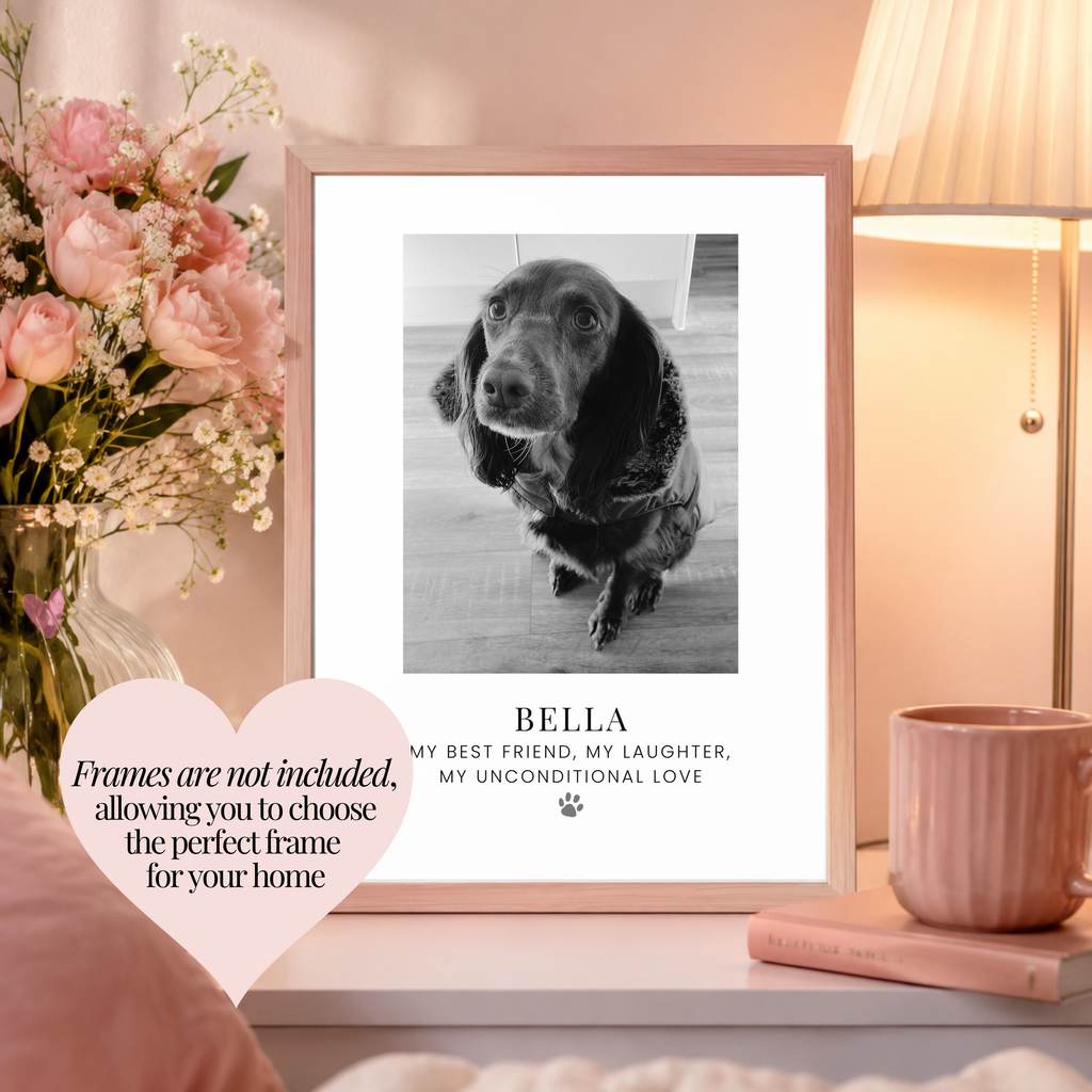 A framed pet photo print featuring a black and white photo of a dog with the text 'my best friend, my laughter, my unconditional love' and a paw print. The frame is displayed on a shelf next to a pink mug, a book, and a vase of pink flowers, with a heart-shaped overlay stating 'frames are not included, allowing you to choose the perfect frame for your home'.