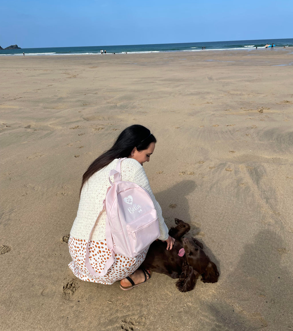 Personalised pink dog backpack used on a beach walk with a Cocker Spaniel.