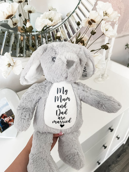 Personalised dog wedding gift bunny toy in grey, styled in a home setting with the text detail 'my mum and dad are married' with the wedding date on the bunny ear, personalised dog owner wedding gift.