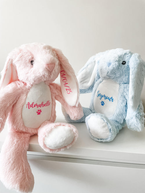 Two personalised bunny dog toys, in pink and blue placed on the side with custom names and dates of birth personalised.