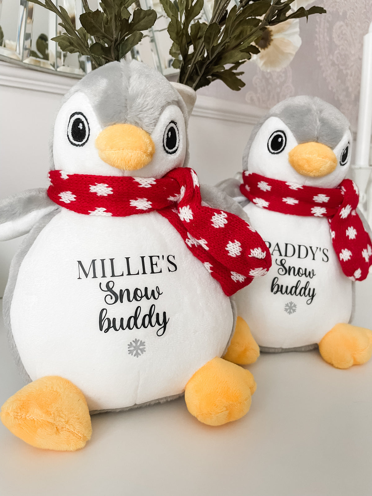 Two personalised penguin Christmas dog toys personalised with dog's names and the words 'Snow Buddy' underneath finished with a silver snowflake symbol on both. A festive Christmas gift for dogs and puppies.