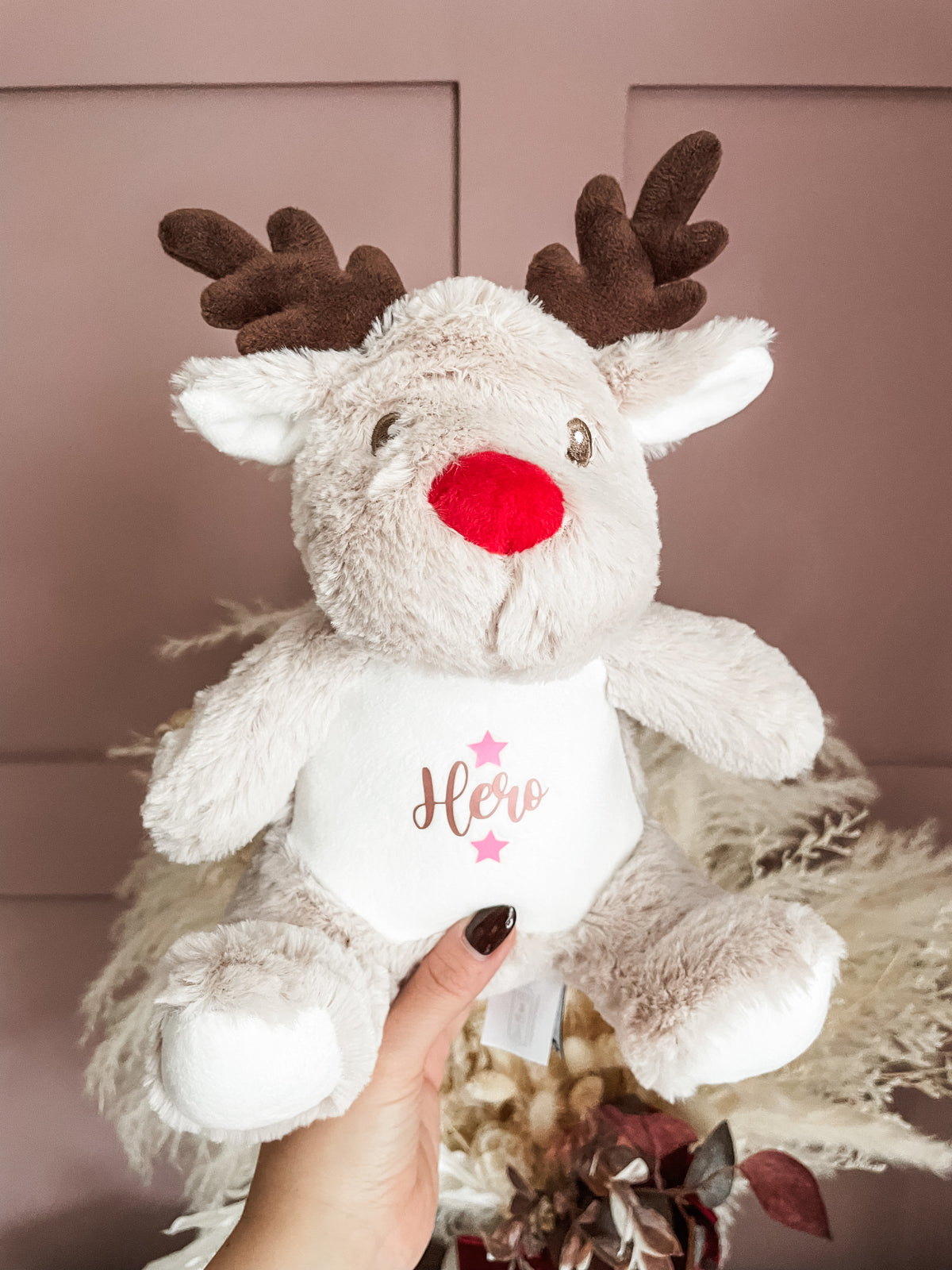 Personalised Christmas dog toy in a reindeer design being held to show the size and plush material design.
