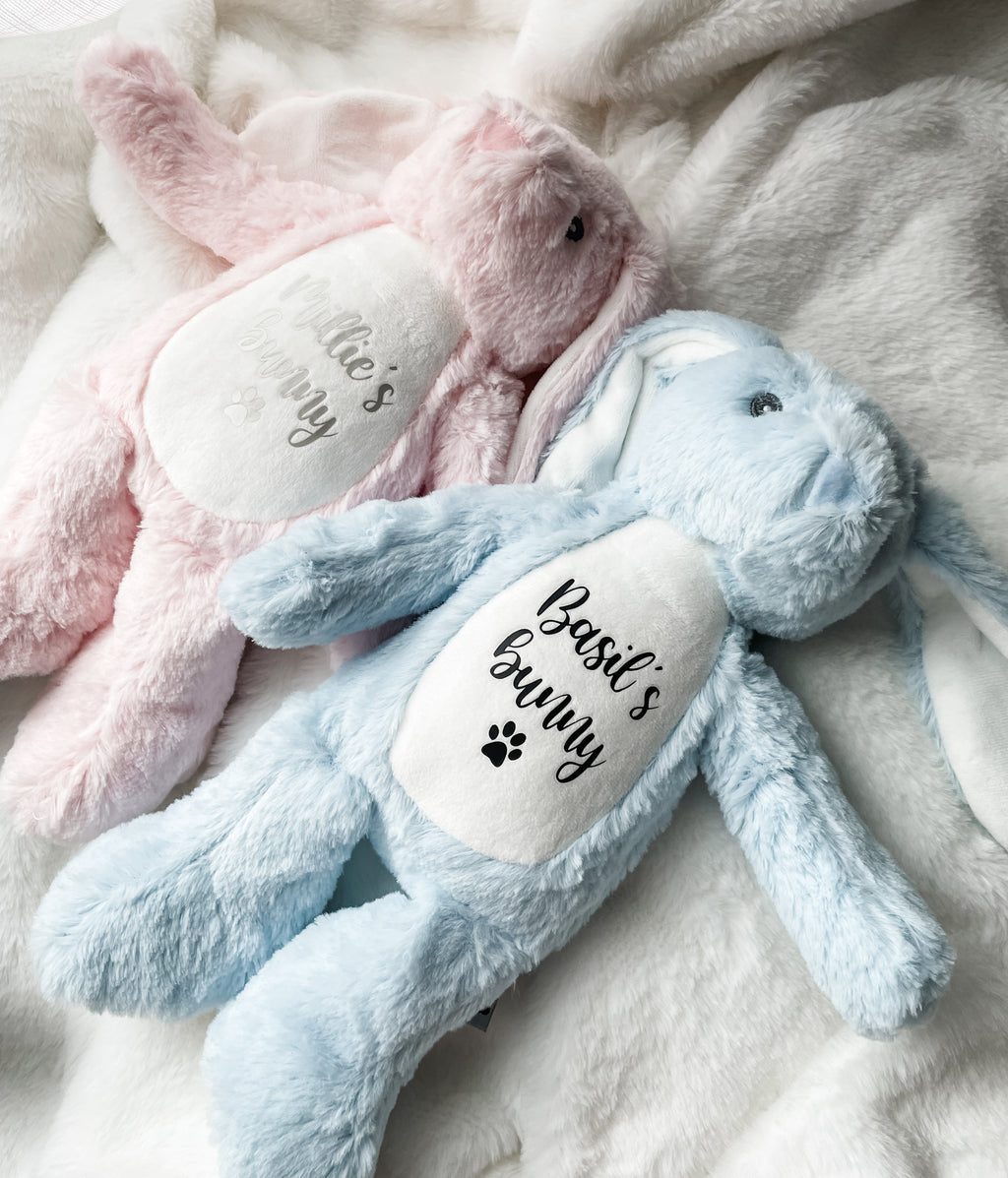 Pink and blue bunny dog toys personalised with dog's name and the word 'bunny' underneath with a paw print symbol.