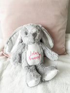 Personalised grey bunny dog toy displayed in a cosy home setting. Custom dog toy with personalised name.