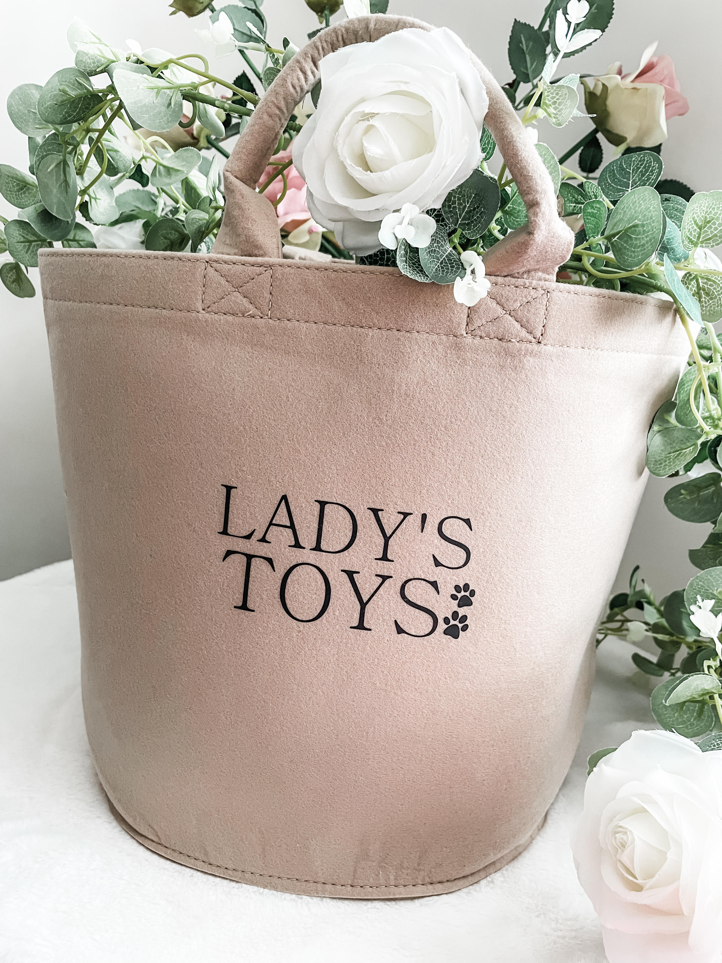 Personalised dog toy storage basket in beige felt with carry handles. Perfect for organising dog toys.